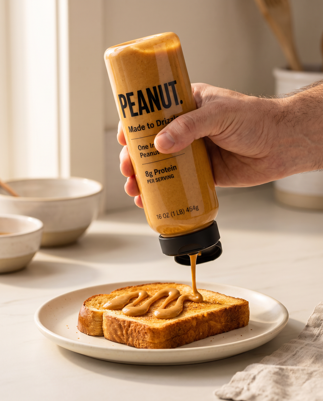 A hand squeezing peanut butter from the bottle onto French toast